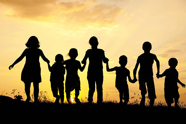 silueta, grupo de niños felices jugando en prado, puesta de sol, s - holding hands child silhouette family fotografías e imágenes de stock