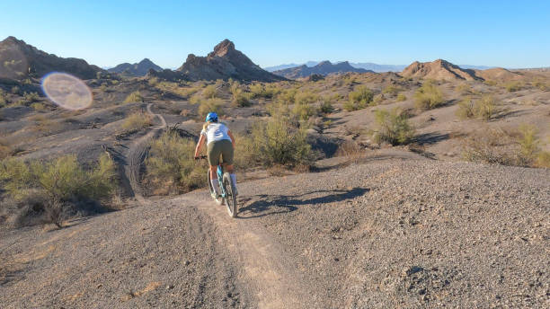 istock Female mountain biker follows trail, in desert 1358480954