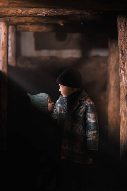 kleine kinder, bruder und schwester, in einem graben, einem einbaum. die nacht, die harten schatten und der dunst. kinder des krieges. - pit house stock-fotos und bilder