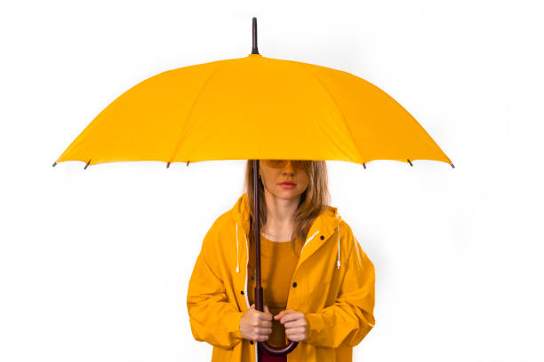 istock A girl in a yellow raincoat stands under an umbrella. Isolate on white background 1358482496