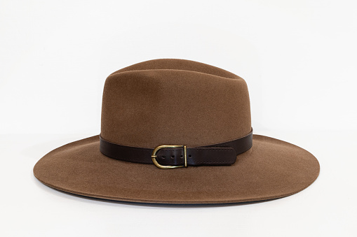 Classic cowboy brown felt hat with strap and copper closure on white background. Side view