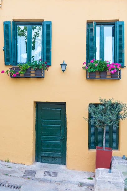 istock Windows with blue shutters on the white wall and blooming pink flowers 1358491956