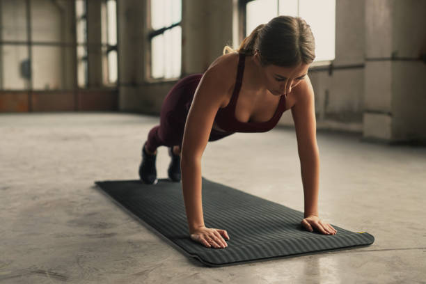 istock Sportswoman standing in plank pose in gym 1358492340