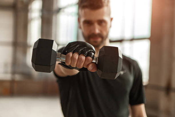 istock Male athlete showing dumbbell during training 1358492359