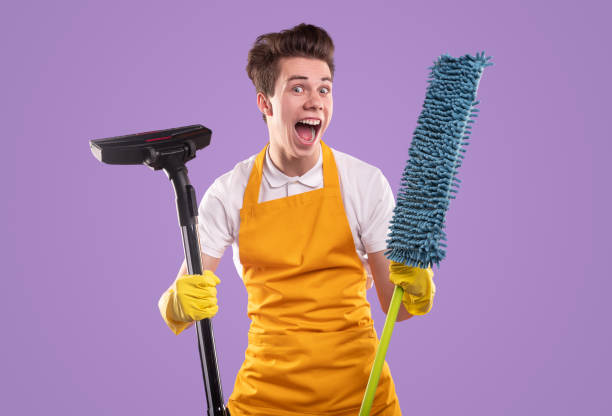 Excited housekeeper with vacuum cleaner and mop stock photo