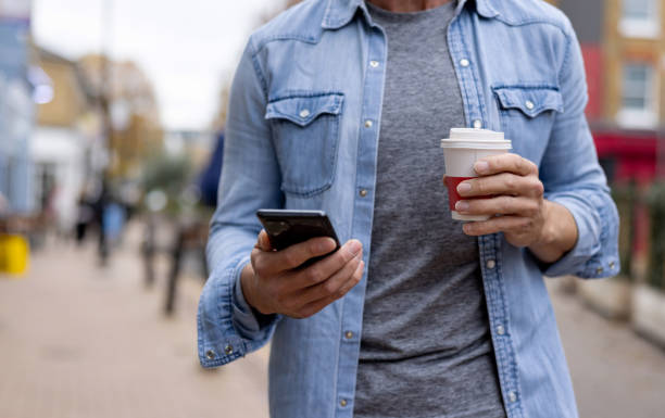 istock Close-up on a man drinking coffee on the go while checking his cell phone 1358492871