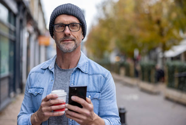 istock Adult man checking his phone on the street while drinking coffee 1358492872