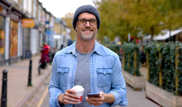 istock Happy man outdoors using his cell phone while drinking a cup of coffee 1358492881