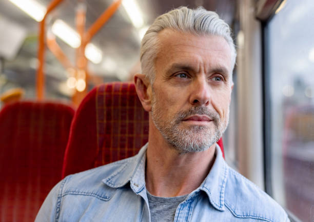 istock Handsome man riding on a train and looking through the window 1358492884