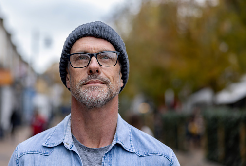 Portrait of a thoughtful man outdoors on a cold day wearing a beanie and glasses