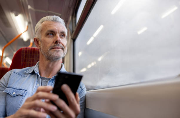 istock Adult man using his cell phone while riding on a train 1358492890