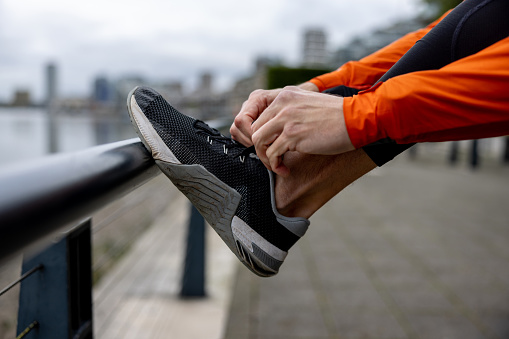 Close-up on a male runner tying his shoelace on the street - healthy lifestyle
