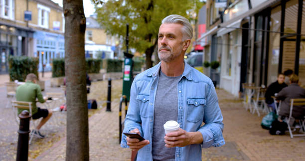 istock Casual man on the street drinking a cup of coffee while using his phone 1358492929