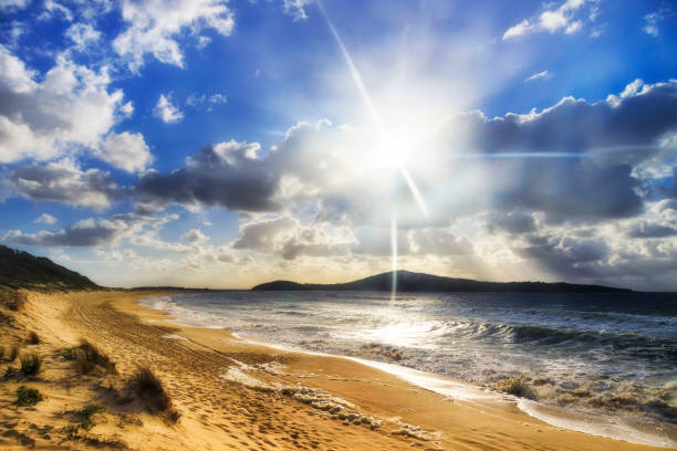 Bright sun disk over stormy cloudy above Fingal island off Fingal bay and beach in Australia - pacific coast.