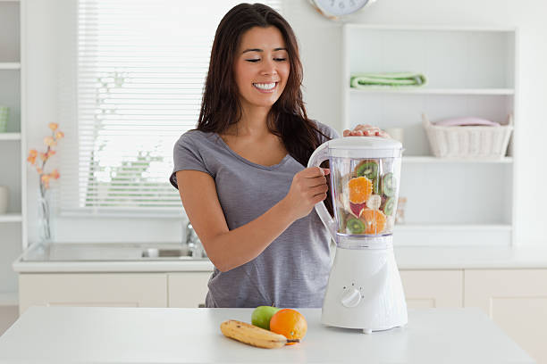 Charming woman using a blender while standing stock photo