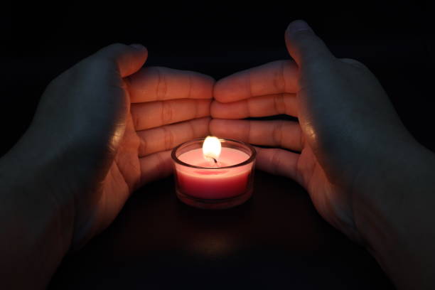 istock Women's hand lighting a candle in the dark. 1358501782