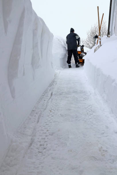 istock A man clears the sidewalk with a snow blower during heavy snowfall 1358503431