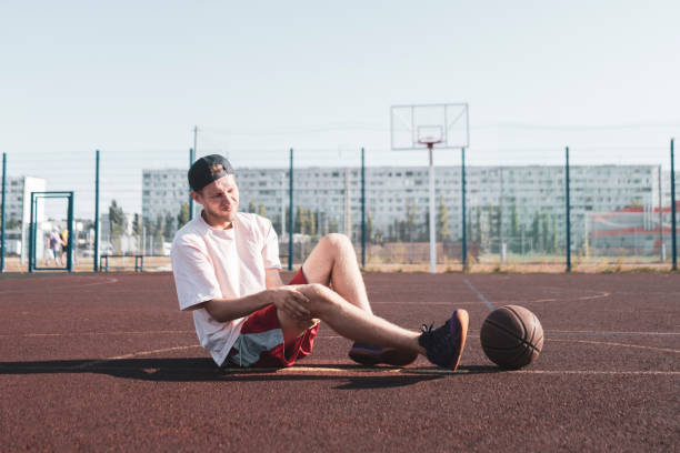 basketball player having an injury, lying on the court and feeling pain stock photo
