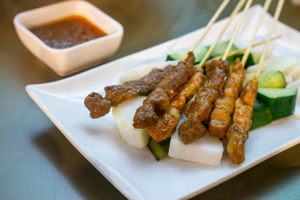 Singaporean-style chicken and beef satay skewers, served with pressed rice (nasi impit), cucumbers, onions and peanut gravy.
