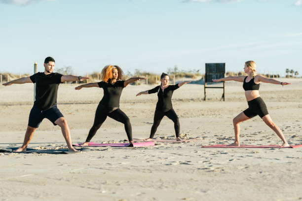 istock Yoga teacher conducting a class with multiethnic people on a beach 1358511808
