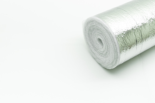 A roll of insulation made of foamed polyethylene with aluminum foil. Thermal insulation with reflective foil. Selective focus, copy space.