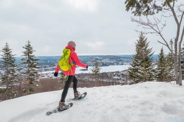 schneeschuhwander im winterwald mit schneebedeckten bäumen an verschneiten tagen. frau auf wanderung im schnee wandern in schneeschuhen lebt gesunden aktiven outdoor-lebensstil. mont tremblant, laurentians, quebec kanada. - snowshoeing snowshoe women shoe stock-fotos und bilder