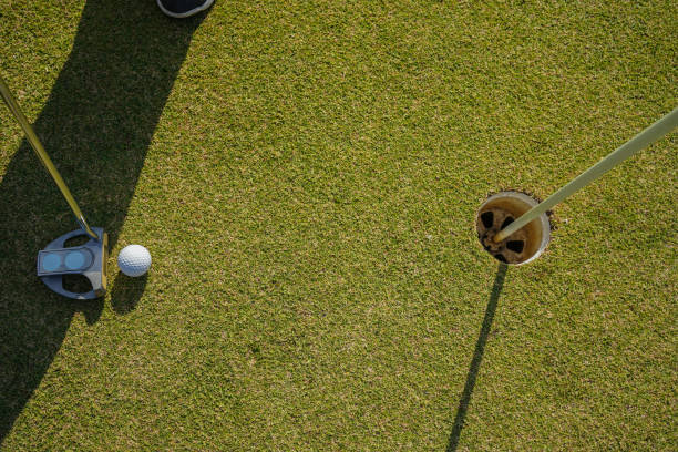 グリーン上にゴルフボールを置くゴルファーの練習トレーニング、夕方の太陽の上にレンズフレア - golf green practicing sports training ストックフォトと画像