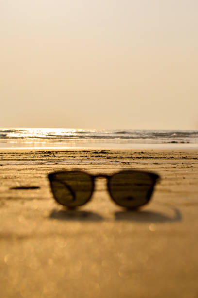 Sun glasses blurred on beach sand with sea during evening light. Blurred sun glasses. Used selective focus.