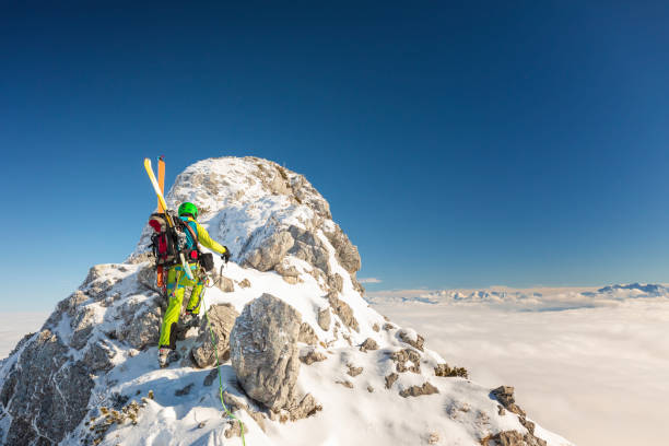 istock Mountaineer man climbs on top snowy mountain with Ski at the backpack 1358535317