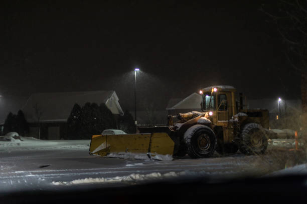 istock Front Loader Snowplow Waiting in Night Blizzard Parking Lot 1358535362