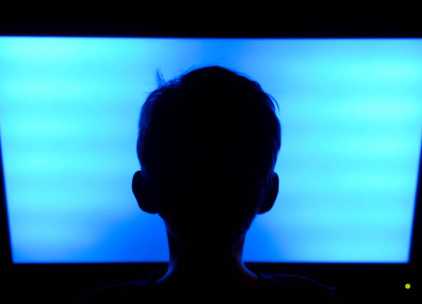 Flat Screen TV Boy Boy (9 years) looking at the typical blue screen of a flat screen television. silhouette of bad boy stock pictures, royalty-free photos & images