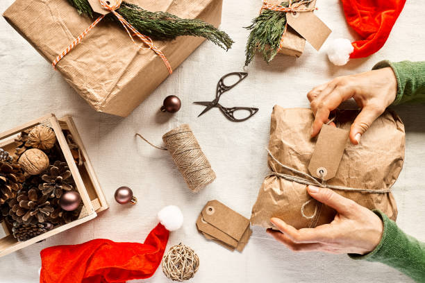 istock Woman's hands holding christmas gift wrapped in craft recycled paper on the table with christmas decoration. Natural aesthetic. Zero waste. Packaging of Christmas gifts.Winter holiday celebration. 1358537310