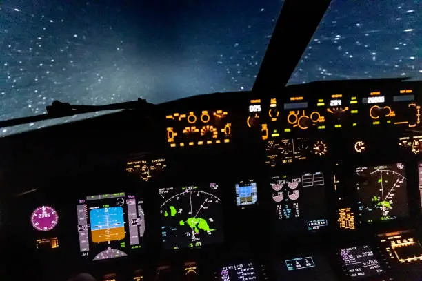 View of a Boeing 737 flightdeck while flying through rain. The airplane's lights are turned on which illuminates the raindrops