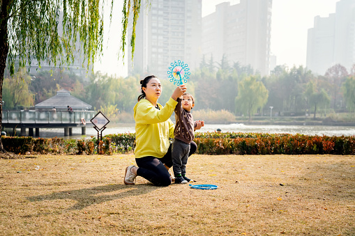 Young asian mother and son having fun in park
