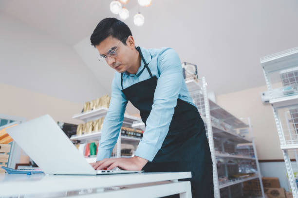 istock Businessman owner staff using computer laptop checking product inventory shelf in grocery store 1358543449