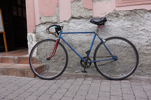 An old men's racing bike in very good condition is leaning against a wall in front of a shop entrance.