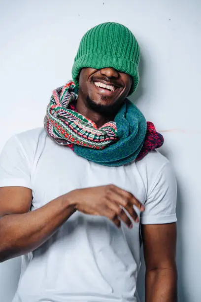 Photo of Laughing silly african american with a green winter hat pulled over his face