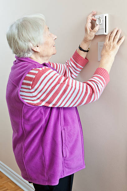 istock Senior woman adjusting her thermostat 135854755