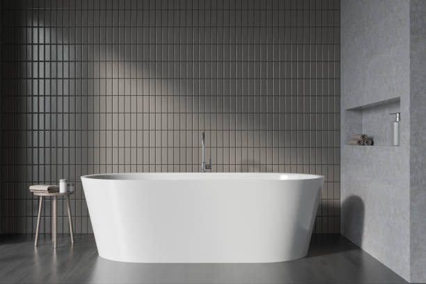 istock Grey bathroom interior with bathtub on black parquet floor, table with gels 1358548674