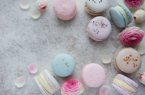 Beautiful colorful tasty macaroons on a concrete background Beautiful colorful tasty macaroons and pink roses on a concrete background bud candy stock pictures, royalty-free photos & images