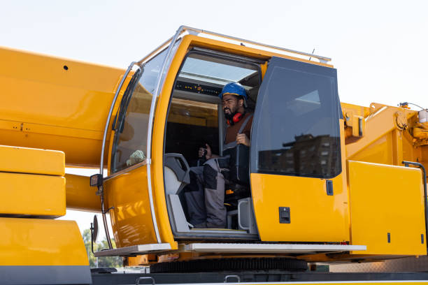 Young man operating a crane, talking with co-worker.  Focus on man in crane.