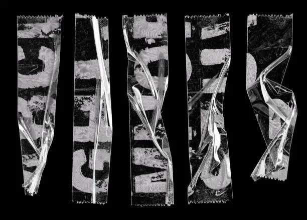 Photo of transparent adhesive tape or strips isolated on black background with alphabet letters