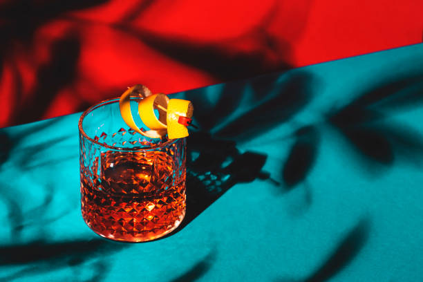 Sazerac, classic alcoholic cocktail with cognac, bourbon, absinthe, bitters, sugar and lemon zest. Dazzling red blue background with hard light and harsh shadows Sazerac, classic alcoholic cocktail with cognac, bourbon, absinthe, bitters, sugar and lemon zest. Dazzling red blue background with hard light and harsh shadows vermouth stock pictures, royalty-free photos & images