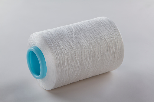 white bobbins of thread , Stacked spools of white thread ,
The cone of white thread isolated on a white background