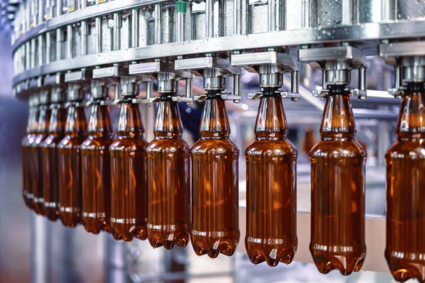 большая разливочная машина, процесс наполнения пластиковых бутылок различными напитками - bottling plant brewery industry food стоковые фото и изображения