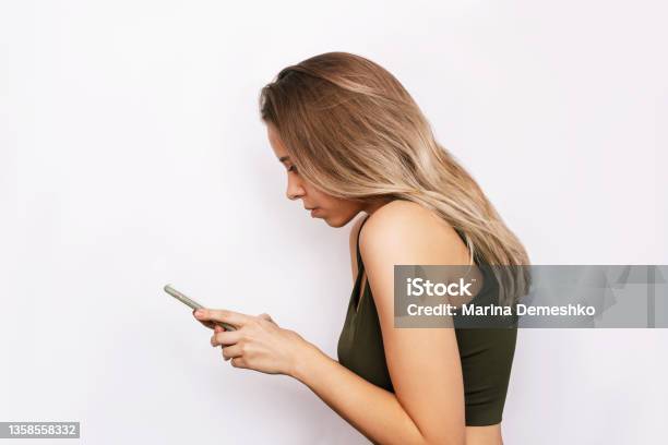 A Young Woman With A Hunched Back Looks At The Mobile Phone Screen Incorrect Back Position Stock Photo - Download Image Now