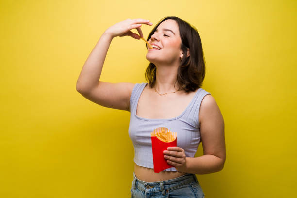 istock Attractive woman eating fries 1358558594