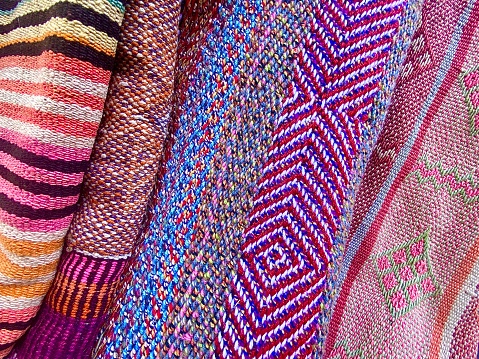 Horizontal close up textures of varied patterned design of thick material fibre vibrant cloth throw rugs