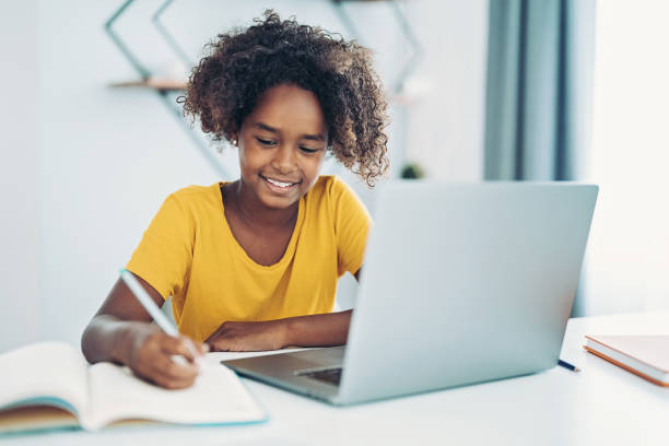 istock Schoolgirl with laptop and textbook 1358566628