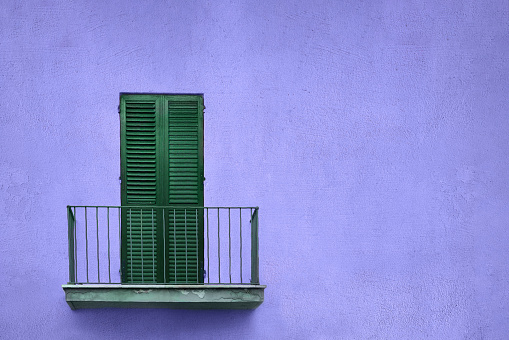 latticed wooden balcony with closed shutters on blue violet color wall with copy space, film grain, noise
